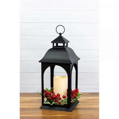 Black ivy and berry LED metal lantern glowing on a white wood background