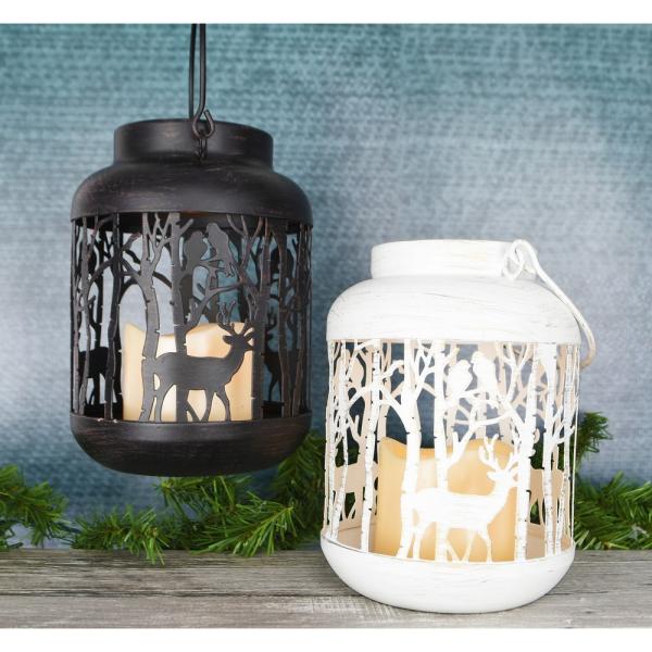 White woodland LED lantern glowing beside a black lantern on a table