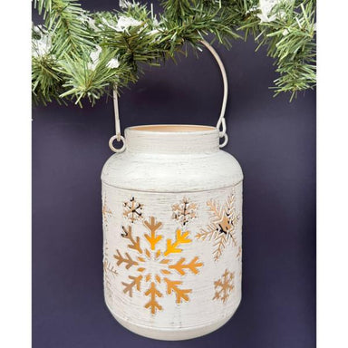 White snowflake LED lantern glowing beneath evergreen branches