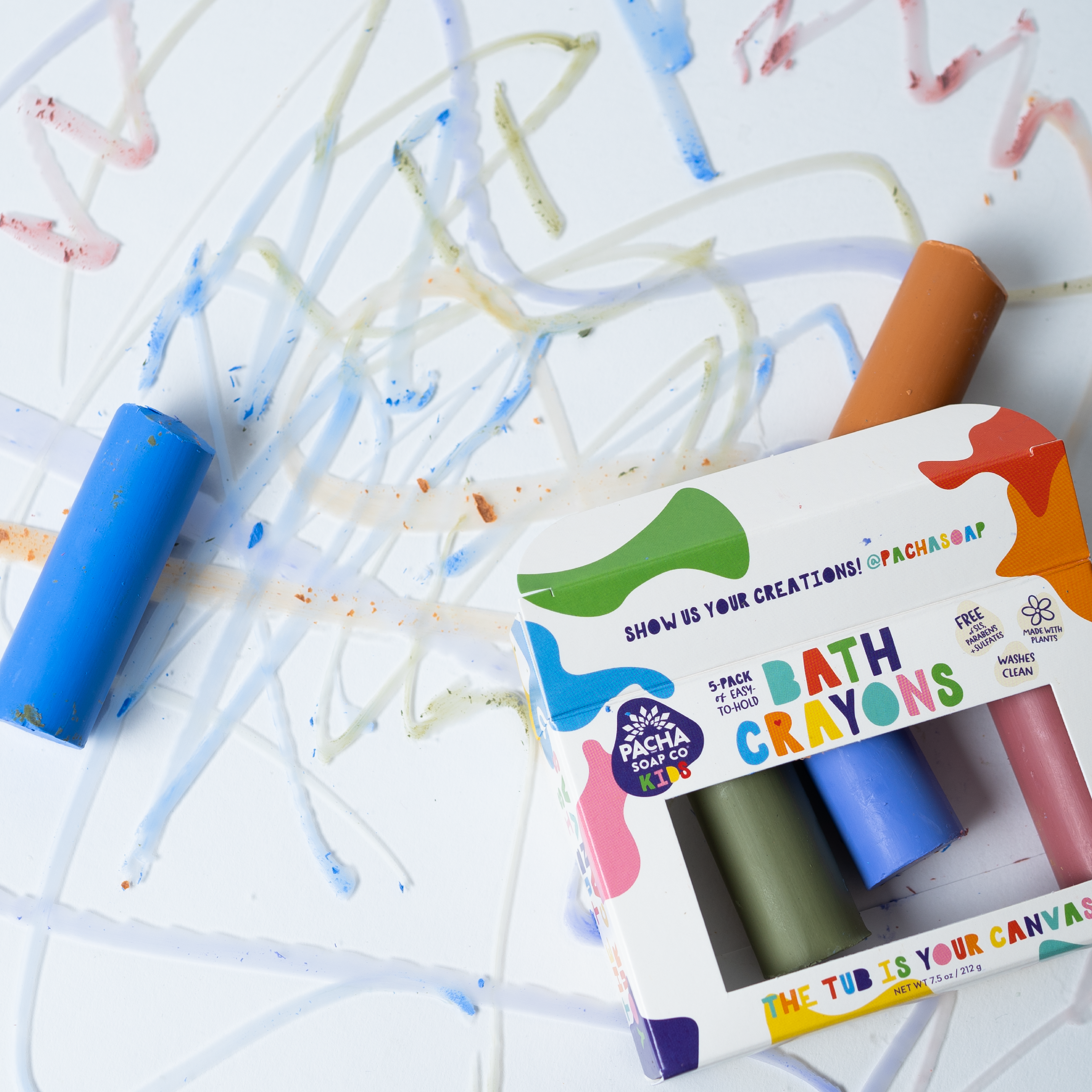 Child drawing on a wet tub wall with Pacha Bath Crayons rainbow colors