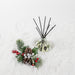 Comfort & Joy Reed Diffuser with black reeds on snowy pinecones and pine branches