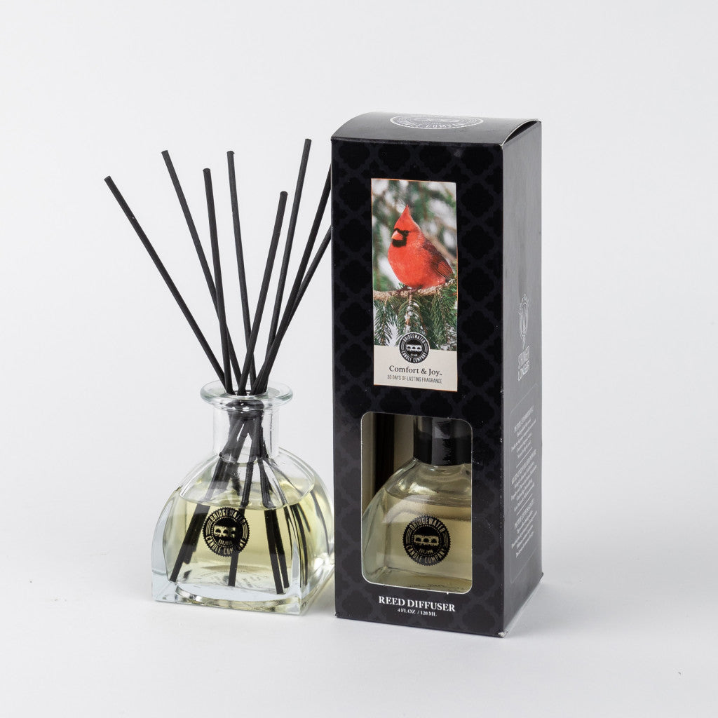 Comfort & Joy Reed Diffuser with black fiber reeds beside its box featuring a red cardinal